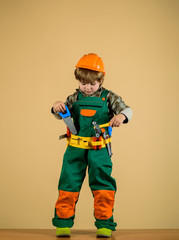 Kid as construction worker. Little repairman. Little boy in helmet and tools. Little boy plays construction worker. Builder. Child game. Tools for building. Little boy in builder's uniform with tools.