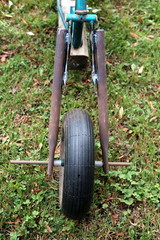 Vorderrad eines selbstgebauten rostigen alten Dreirad auf grüner Wiese im Sommer auf einem...