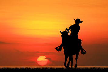 Fototapeta na wymiar silhouette Cowboy riding a horse on sunrise