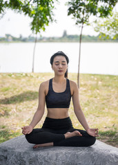 Fototapeta na wymiar Young beautiful woman practices yoga and meditates outdoor at the mountain. Female doing yoga and meditate to relax and release stress.
