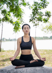 Fototapeta na wymiar Young beautiful woman practices yoga and meditates outdoor at the mountain. Female doing yoga and meditate to relax and release stress.