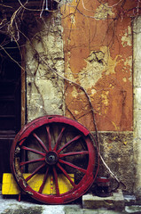 Obraz premium Old Sicily: Red Wagon Wheel & Time-Worn Wall