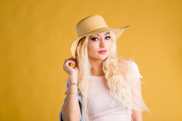 Beautiful young woman in sun hat on yellow background