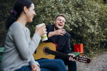 Fototapeta na wymiar Man and woman spending time together with guitar outdoors