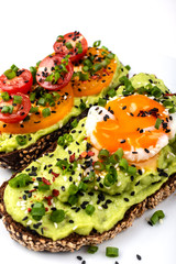 Sandwiches with avocado guacomole, egg and tomatoes, green leek and sesame seeds. Healthy breakfast or snack on a white background.