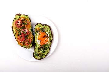 Sandwiches with avocado guacomole, egg and tomatoes, green leek and sesame seeds. Healthy breakfast or snack on a white background. Copy space.