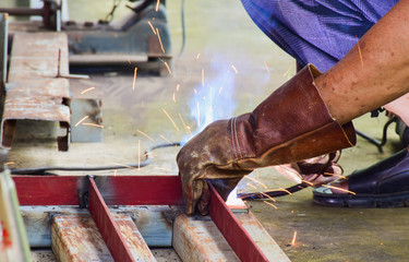 Team of welder work with welding metal part. Welder wear leather glove for welding work.