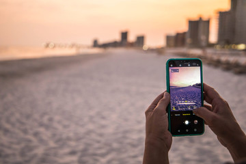 new cellular cell mobile phone at the beach taking a picture of the sunset