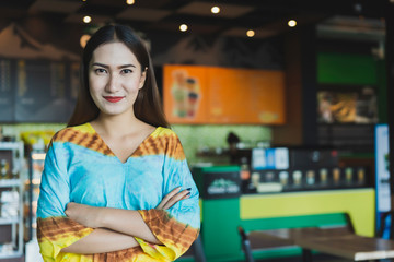 Start up of enterprise, young Asian business women leader the new business or Start a franchise business self-confident. Smart small business owner standing with crossed arms on coffee shop background