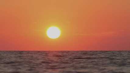 Sea sunset. Time lapse of the large sunset as the sun sets into the horizon above the sea.