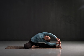 Fototapeta na wymiar Caucasian woman sitting in yoga pose Parivrtta Janu Sirsasana. Studio shot