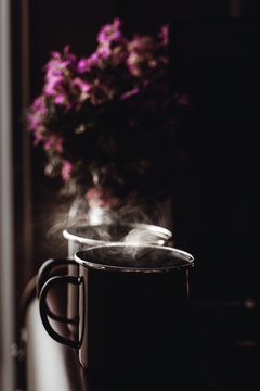 Kaffetassen mit frischem Kaffee vor einem Blumenstrauss