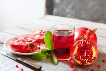 Pomegranate juice with fresh pomegranate fruits on wooden table