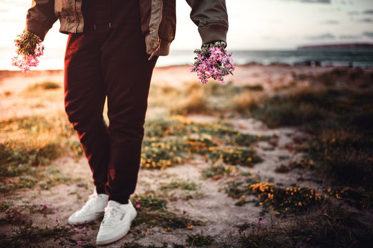 mann geht am strand mit einem blumenstrauss in der hand