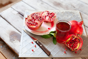 Pomegranate juice with fresh pomegranate fruits on wooden table