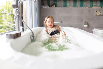 Happy little girl is playing in the bath