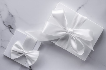 Luxury wedding gifts with silk bow and ribbons on marble background