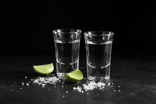 Vodka in shot glass on black background with a blank space for a text, Russian vodka with salt and lemon