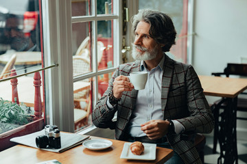 Handsome old man drinking coffee in cafe