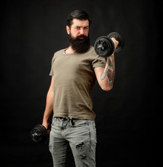 Fototapeta na wymiar Handsome man lifting dumbbell at gym. Healthy sports lifestyle, fitness concept. Athletic young male fitness model holds dumbbell. Fit young man in sportswear holds dumbbell during workout in gym.
