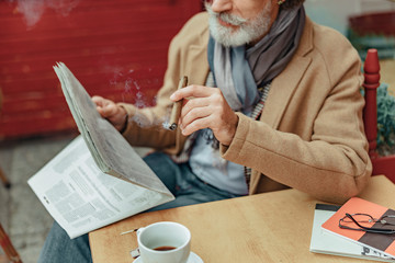 Senior man with cigar reading daily news