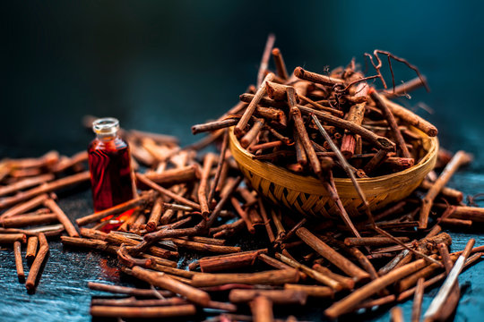 Bunch of Indian madderwort or madder root in a brown-colored basket on the black wooden surface also known as manjistha/manzistha/Rubia cordifolia/madder etc with its essential essence/concentration.