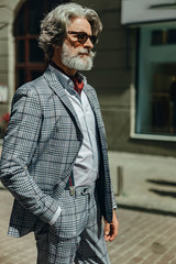 Fototapeta na wymiar Elegant gentleman in sunglasses standing on the street