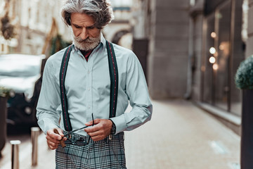 Elegant senior man holding cigar and sunglasses