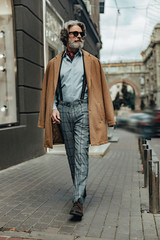 Elegant senior man with cigar walking on the street