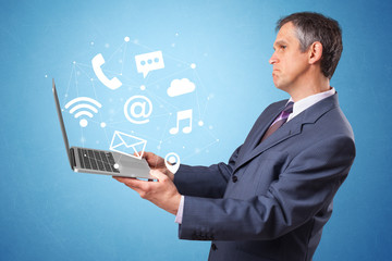 Man holding laptop with online services symbols