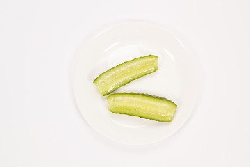 Two halves of cucumber on a plate on a white background. Sliced cucumber on a plate.
