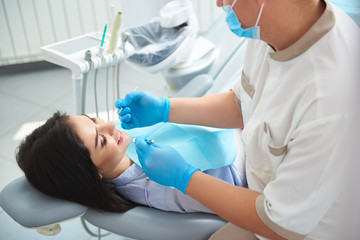 Happy young female receiving teeth treatment in clinic