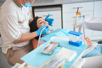 Fototapeta premium Dentist in protective mask is treating teeth