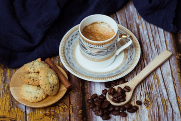 Tasse de café en porcelaine ancienne biscuits à la cannelle et grains de café sur une table en bois vintage	