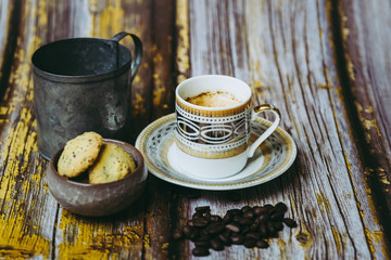 Tasse de café en porcelaine ancienne biscuits à la cannelle et grains de café sur une table en bois vintage	