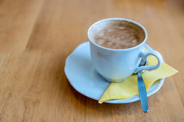 a cup of coffee on a light wooden table