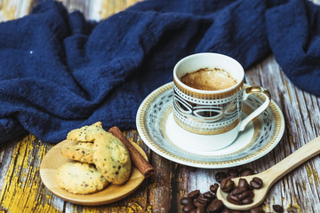 Tasse de café en porcelaine ancienne biscuits à la cannelle et grains de café sur une table en bois vintage	