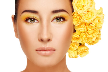 Portrait of young beautiful woman with fancy makeup and yellow roses in hair