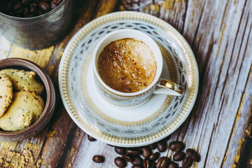 Tasse de café en porcelaine ancienne biscuits à la cannelle et grains de café sur une table en bois vintage	