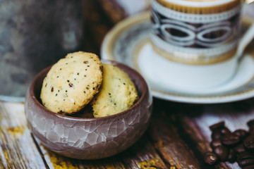 Tasse de café en porcelaine ancienne biscuits à la cannelle et grains de café sur une table en bois vintage	