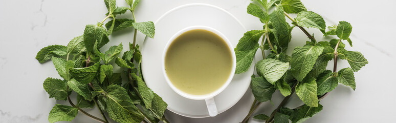 flat lay with cup of green matcha tea with mint on white table