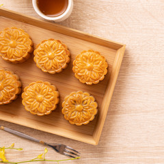 Obraz na płótnie Canvas Moon cakes with tea on bright wooden table, holiday concept of Mid-Autumn festival traditional food layout design, top view, flat lay, copy space.