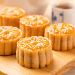 Moon cakes with tea on bright wooden table and serving try, holiday concept of Mid-Autumn festival...
