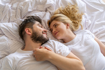 Smiling couple lying down together in bedroom