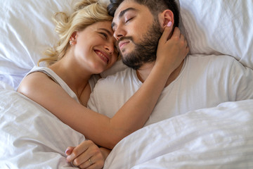 Happy young female lying near boyfriend in bed