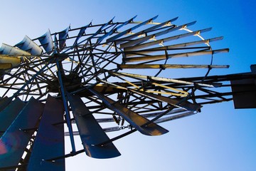 Low angle close up of isolated antique metal wind wheel turbine on steel tower against blue cloudless sky near Zaanse Schans, Netherlands