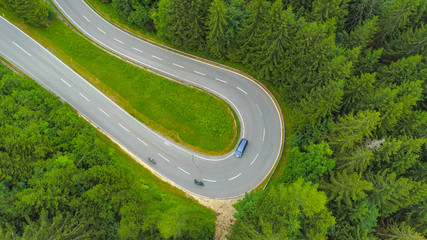 AERIAL: Motorcycles and a car driving through hairpin turn on undulating road