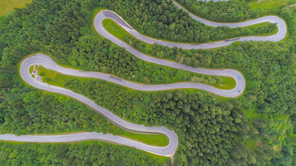 AERIAL: Cars driving along scenic mountain highway with sharp hairpin turns - obrazy, fototapety, plakaty