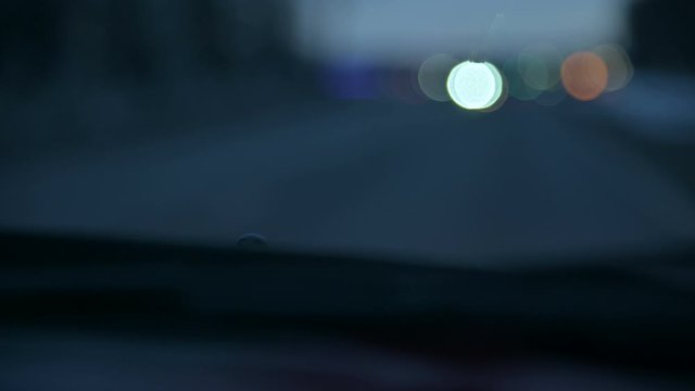 Abstract background blurred view of the lights of oncoming cars on a country road at dusk or in the early morning. Low key defocus bokeh of headlights from POV