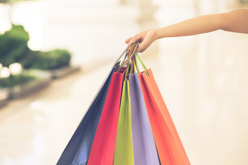 Woman hand holding colorful shopping bags on blurry background